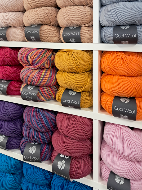 Nahaufnahme von drei Wollregalen im Lanavera Laden, die eine grosse Auswahl der Marke Lana Grossa Cool Wool in vielen Farben zeigen.